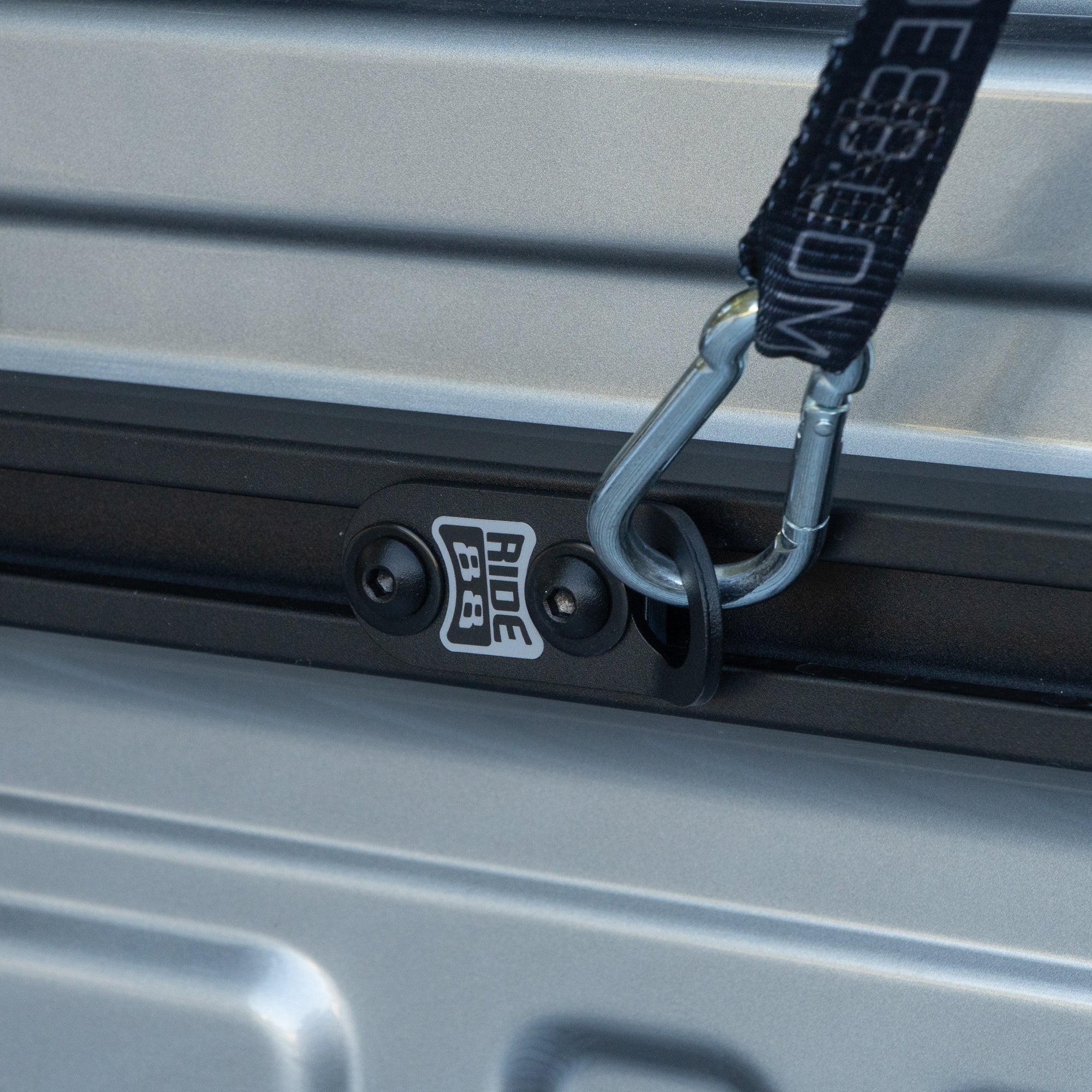 A U-Track Tie-Down Anchor mounted to a U-Track and holding a Tie-Down Strap.