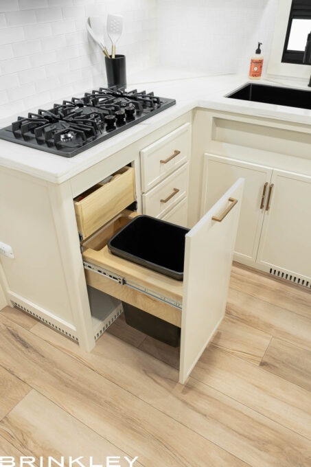 A Large Pull-Out Trash Bin si one of many things that Makes for the Best Travel Trailer RV Interiors and Kitchen Spaces.