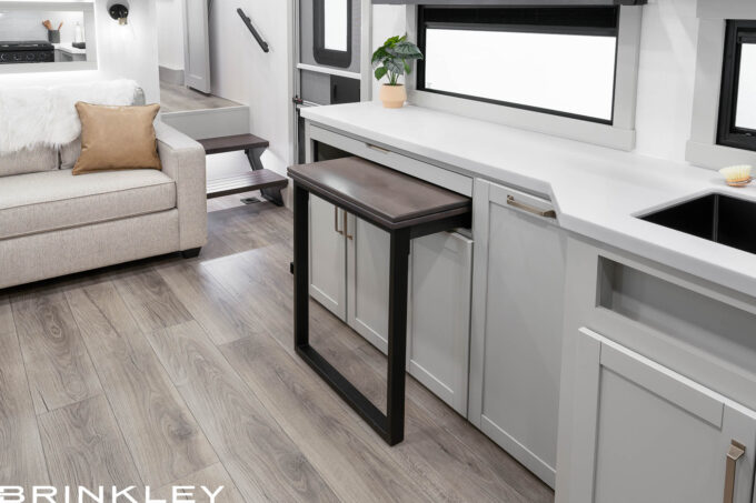 Luxury 2026 Brinkley Model Z 2810 bunkhouse Fifth Wheel dining room featuring the versatile Dinesk sliding table stowed against the wall to create an open floor plan.