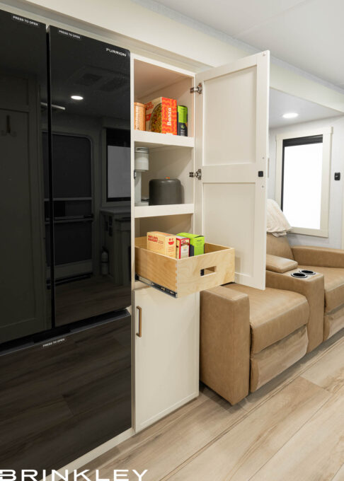 Large pantry and 12v refrigerator in the Brinkley Model I 235, showcasing the high-quality construction of the best built travel trailers. The pantry features solid hardwood cabinetry with heavy-duty pull-out dovetail drawers, offering residential-style smart storage next to a premium high-capacity freezer.
